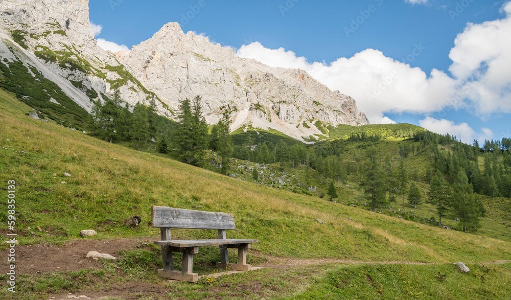 Beautiful alpine landscape with an empty wooden resting bench in the foreground. summer, day, Austria, Alps.