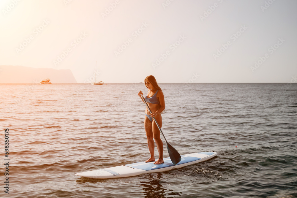 Woman sea sup. Close up portrait of happy young caucasian woman with long hair looking at camera and smiling. Cute woman portrait in a blue bikini posing on sup board in the sea