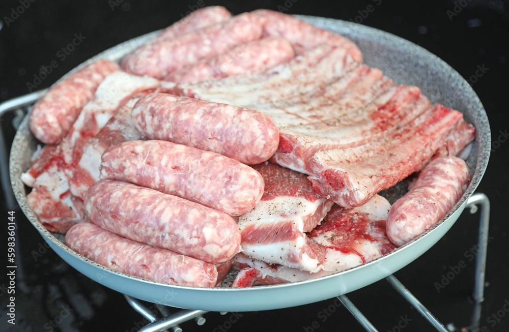 raw sausages and pork ribs ready to be grilled on the alfresco barbecue raw sausages and pork ribs ready to be grilled on the alfresco barbecue