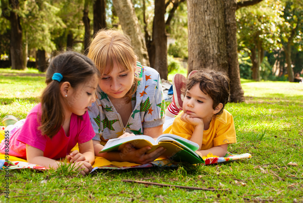Joyful family in the park on the grass reading a book