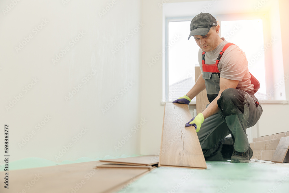 Professional builder man laying laminate flooring at home