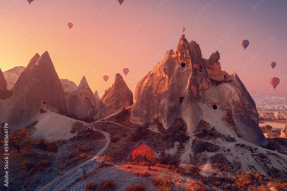 Old ancient home cave in big stone, hot air balloons fly over deep canyons, valleys Cappadocia Goreme National Park, Turkey Travel tourist concept - obrazy, fototapety, plakaty 
