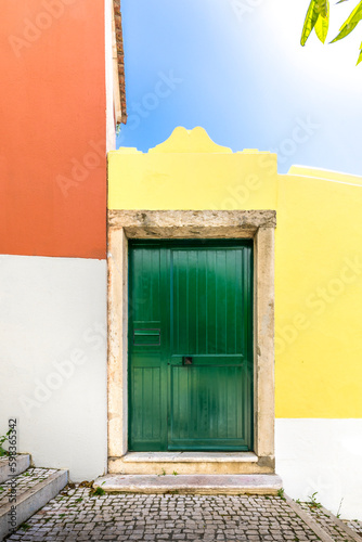 Lisbon, Portugal - April 25, 2023: Beautiful green door with a yellow and orange facade in Lisbon, Portugal