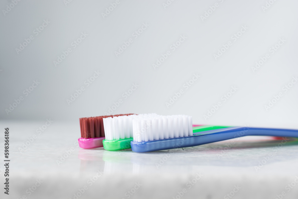 Blue, pink and green toothbrush with white bristles on a white background, colorful toothbrushes with copyspace Blue, pink and green toothbrush with white bristles on a white background, colorful toothbrushes with copyspace