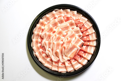 Premium slices Kurobuta (Black Pig) pork with high-marbled texture on circle black plate served for Sukiyaki and Shabu. Top view isolated on white background. 