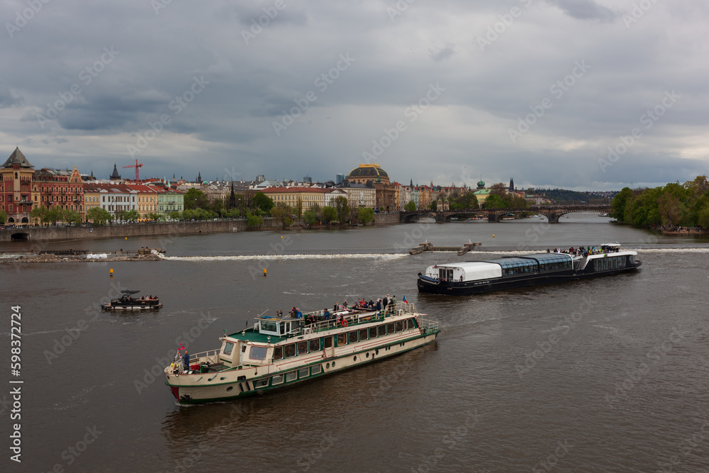 HDR of Vltava Moldau river in Prague with dark sky. The river passes in the middle of the city center, the sky is dark threatening, cruise ships for tourists roam the river.