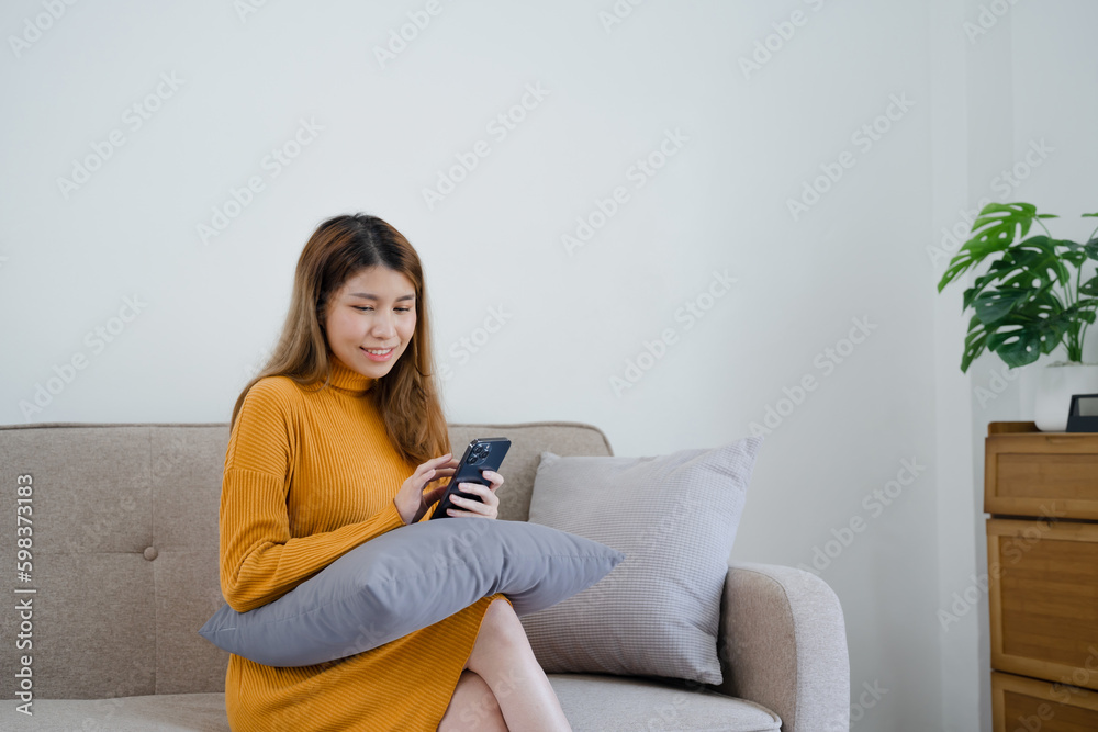 Asian girl using cell phone for checking social media at home holding smartphone in morning Asian girl using cell phone for checking social media at home holding smartphone in morning
