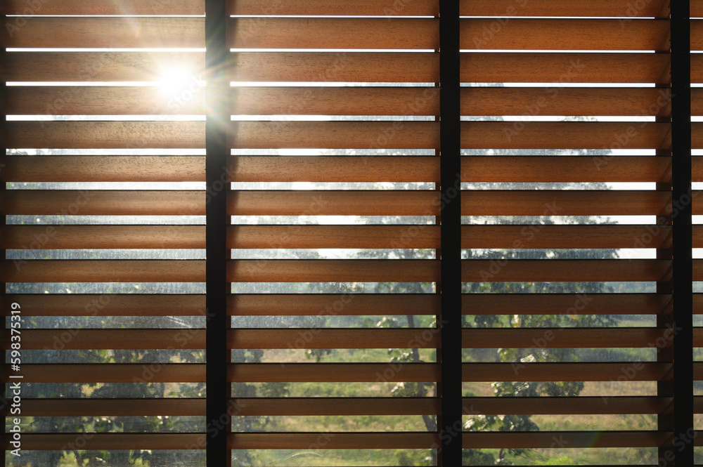 Close-up brown wooden blinds. lighting range control sunlight coming from a window. decoration interior. Modern jalousie. Close-up brown wooden blinds. lighting range control sunlight coming from a window. decoration interior. Modern jalousie.