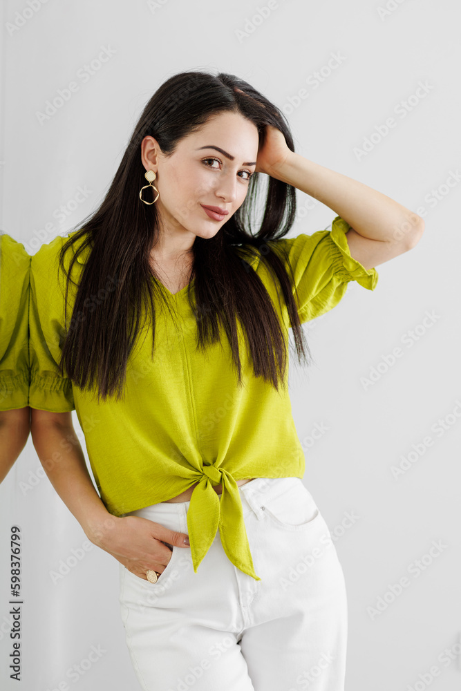 Attractive smiling young woman posing next to the mirror in studio
