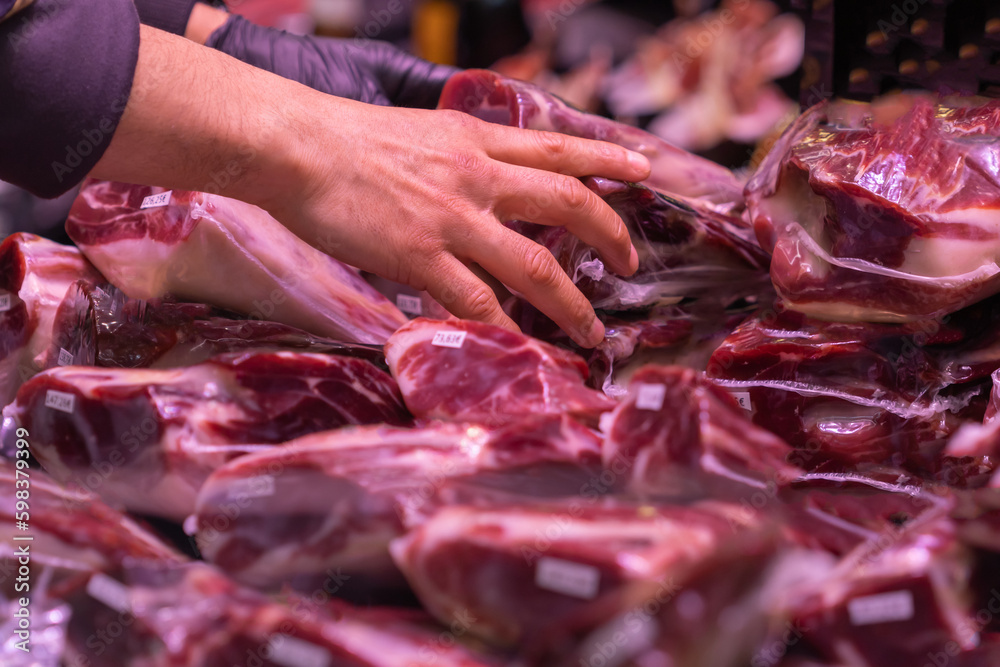 Hand of unrecognizable charcuteto wrapping pieces of Iberian pork in Extremadura (Spain).