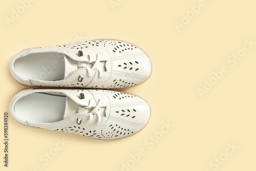 Pale white female shoes on yellow backdrop. Flat lay, top view trendy fashion feminine background.