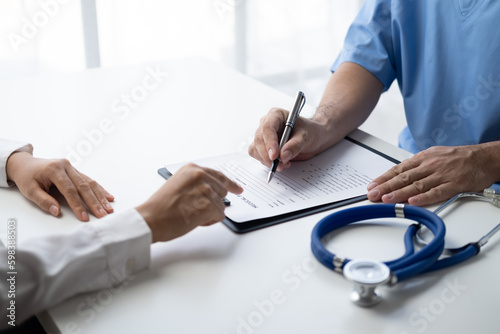 Close up view of doctor in doing paperwork at workplace, filling paper medical records.