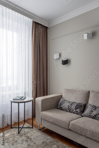 part of the interior in beige and coffee tones, a corner in the living room, a sofa, a coffee table, a window with curtains