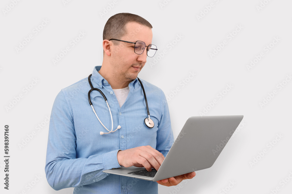 Portrait of a male doctor with a laptop on a light studio background. Portrait of a male doctor with a laptop on a light studio background.