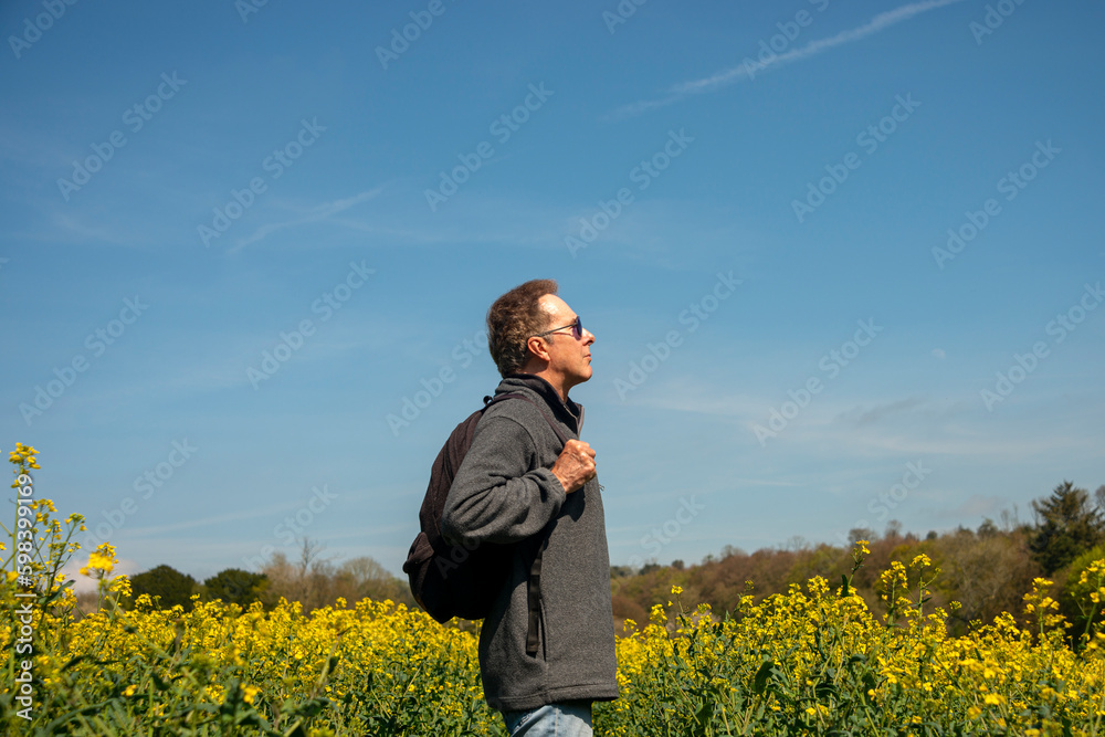 man with a backpack walking through a yellow field, looking up. Getting away from it all concept. man with a backpack walking through a yellow field, looking up. Getting away from it all concept.