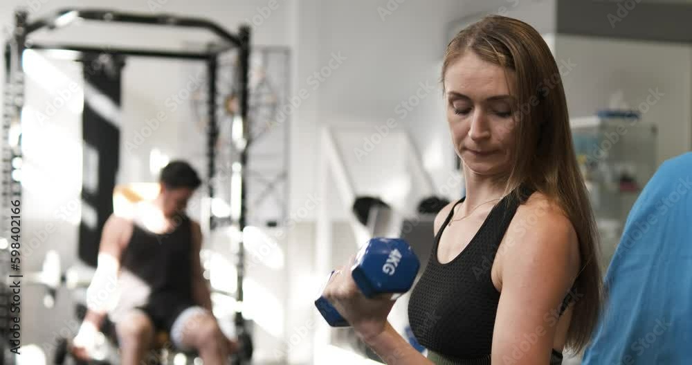 Fit lady exercising with dumbbells in sports center Fit lady exercising with dumbbells in sports center