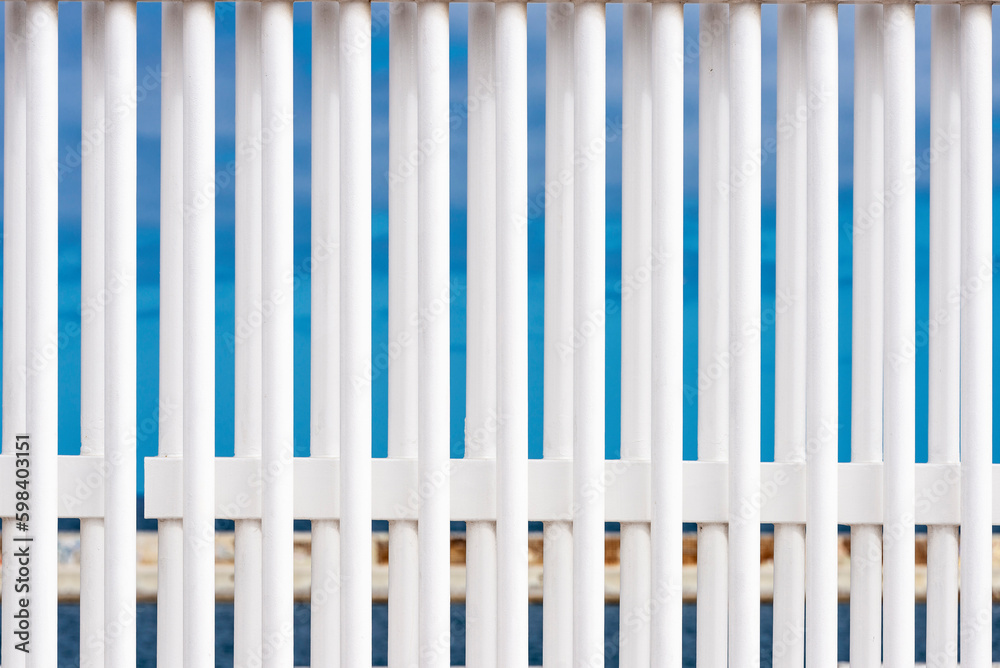 Bars of a white fence against the blue sky Bars of a white fence against the blue sky