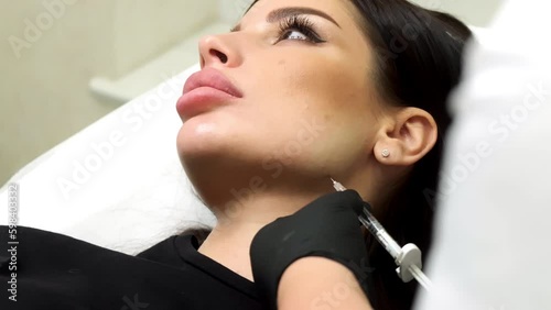 The cosmetologist corrects the shape of the cheekbones by cosmetic injections. The doctor injects hyaluronic acid into the woman's skin as a facial rejuvenation procedure.