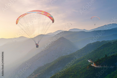 Landscape of flying paraglider over idyllic mountains with haze at sunset with soft light