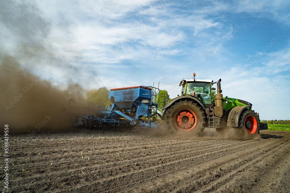 Obraz premium Trecker und Maislegemaschine verschwinden schon fast auf den Acker, so staubt es beim Maislegen.