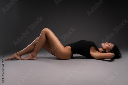 Slim woman in bodysuit lying on floor