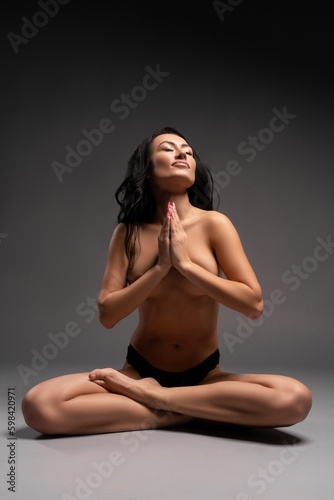 Slim topless woman meditating in studio