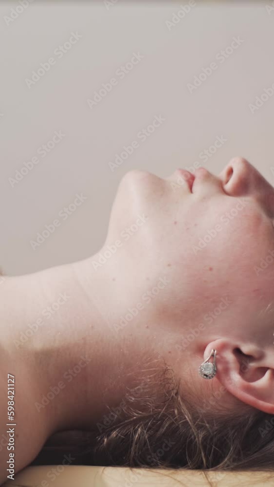 Attractive young woman in spa salon. A masseuse massages a woman's face and neck. Relaxation, stress relief and healing of soul and body in the wellness center.