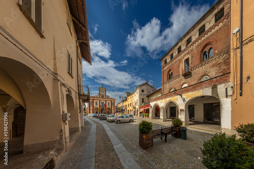 Vigone, Turin, Piedmont, Italy - April 29, 2023: Civic Palace square with the Palace of the Princes of Acaja and the town hall in the background, arcades and cobblestone street with stone guides .