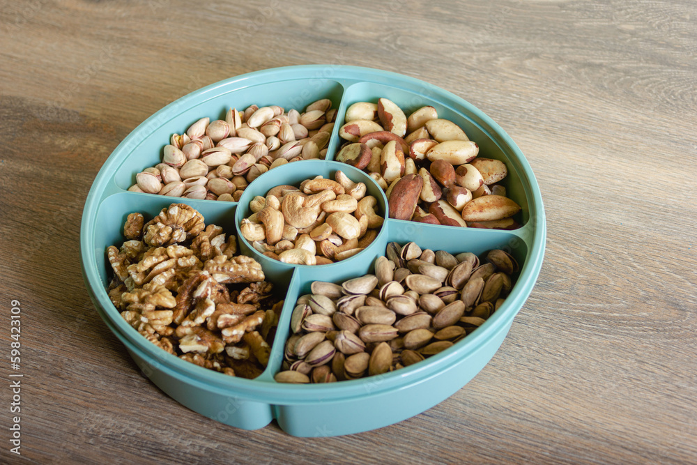 Mix of nuts in a container on a wooden table Mix of nuts in a container on a wooden table