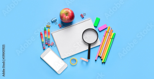 Set of school stationery with mobile phone and apple on blue background