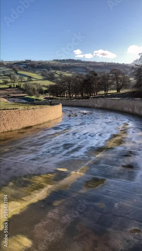 A panning shot of the Victorian stone spillway at Swinsty Reservoir with the scenic rolling hills of North Yorkshire in the background. Taken on a sunny day - Nr Harrogate, UK photo