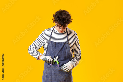 Male gardener with secateurs on yellow background