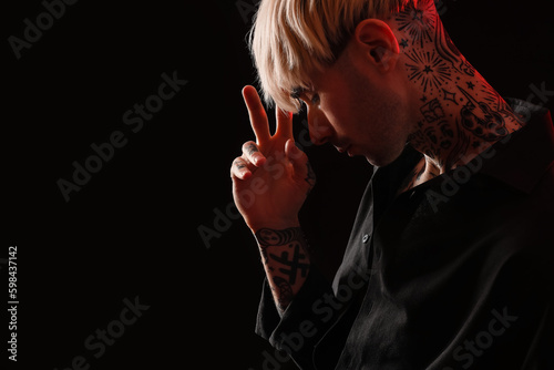 Tattooed young man on dark ...