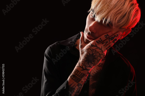 Tattooed young man on dark ...