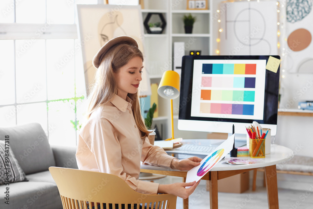 Female graphic designer working with color palette at table in office