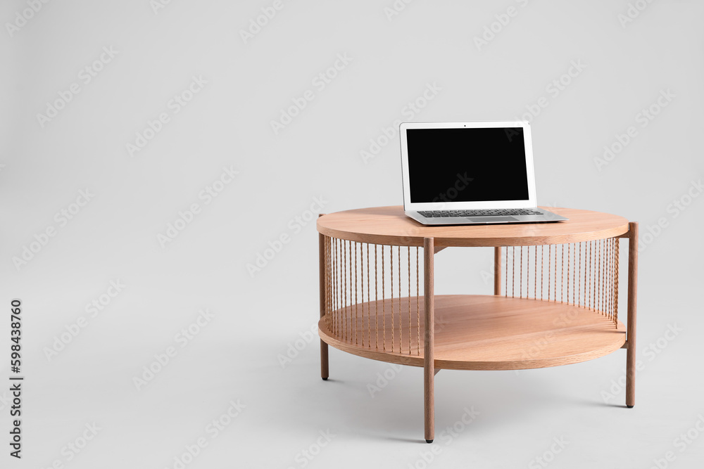Wooden coffee table with modern laptop on grey background Wooden coffee table with modern laptop on grey background