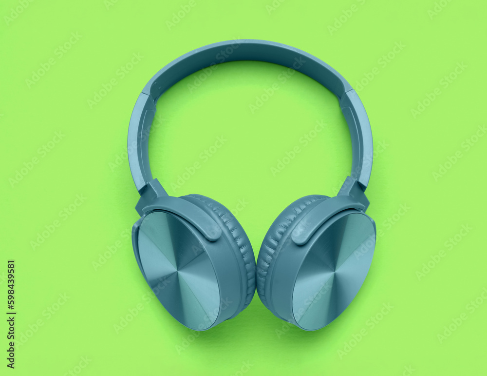 Modern blue headphones on green background