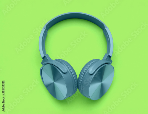 Modern blue headphones on green background