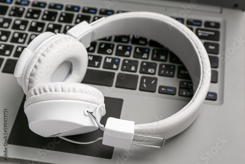 Modern white headphones on laptop, closeup