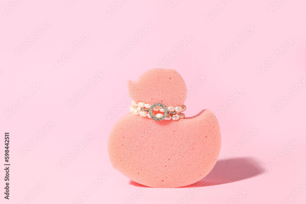 Sponge in shape of duck with jewelry on pink background Sponge in shape of duck with jewelry on pink background