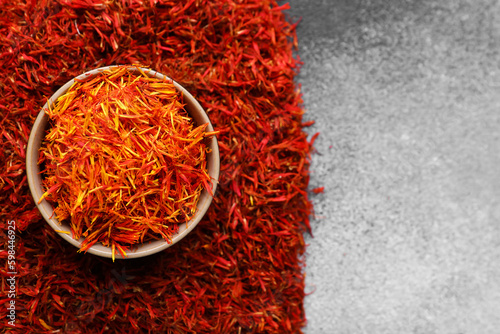 Bowl with pile of saffron on grey grunge background