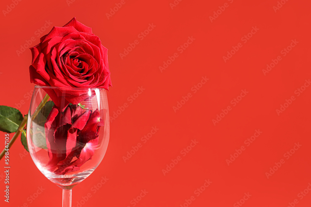 Glass with petals and beautiful rose on red background Glass with petals and beautiful rose on red background