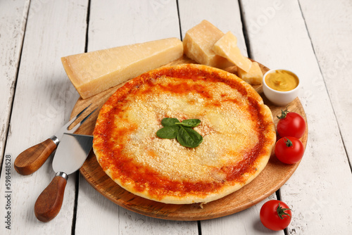 Board of tasty pizza with parmesan cheese, basil and sauce on light wooden background