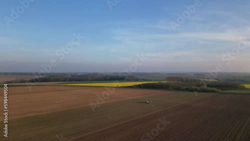 Tractor and field Aerial view. Farm tractor with trailer seeder making sowing agricultural field. Process sowing plowed field. Machinery working on farming field. Agriculture equipment Rural France