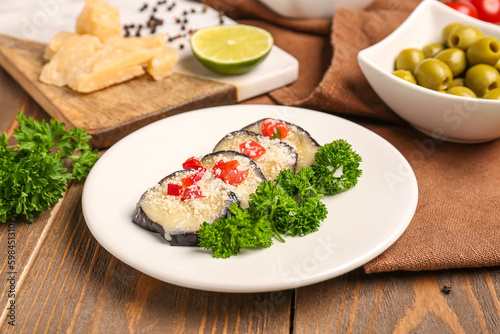 Plate with tasty baked Eggplant Parmesan on wooden background