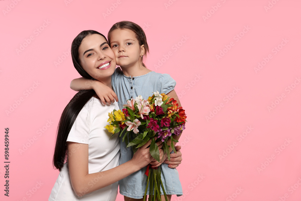 Happy woman with her daughter and bouquet of flowers on pink background, space for text. Mother's day celebration Happy woman with her daughter and bouquet of flowers on pink background, space for text. Mother's day celebration