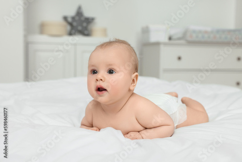 Cute baby lying on white bed at home