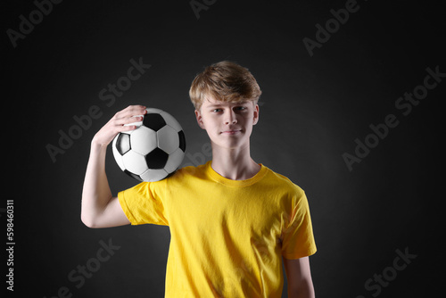 Teenage boy with soccer ball on black background