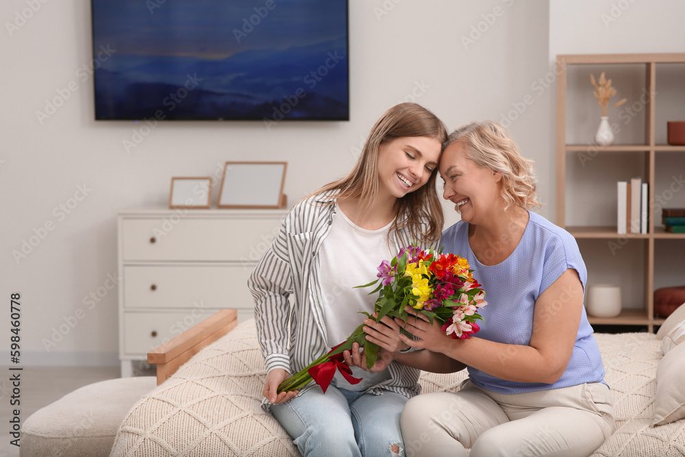 Young daughter congratulating her mom with flowers at home. Happy Mother's Day Young daughter congratulating her mom with flowers at home. Happy Mother's Day