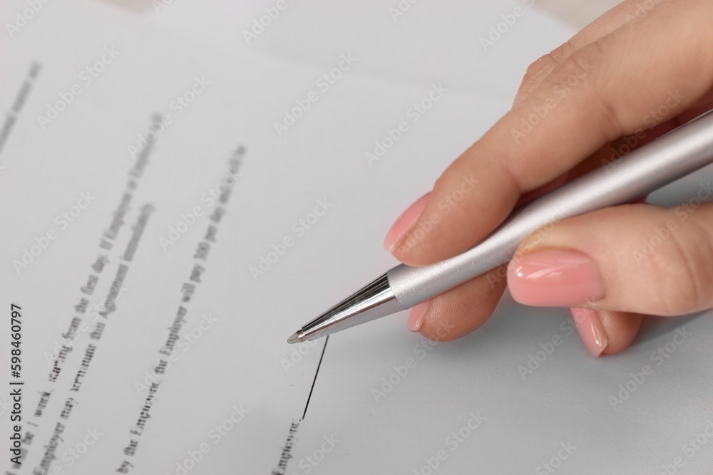 Woman signing document with pen, closeup view Woman signing document with pen, closeup view